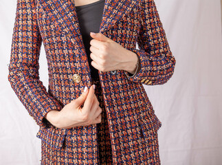 Positive businesswoman fastens button on tweed jacket. High quality photo