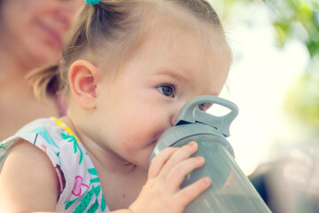 Toddler drinks water in nature. The child and his mother made a halt in a hike