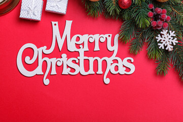 beautiful branches of a Christmas tree with cones and toys on a red background with the inscription Merry Christmas