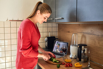 A young woman prepares dinner or lunch from video recipes. Culinary blogs. Online cooking
