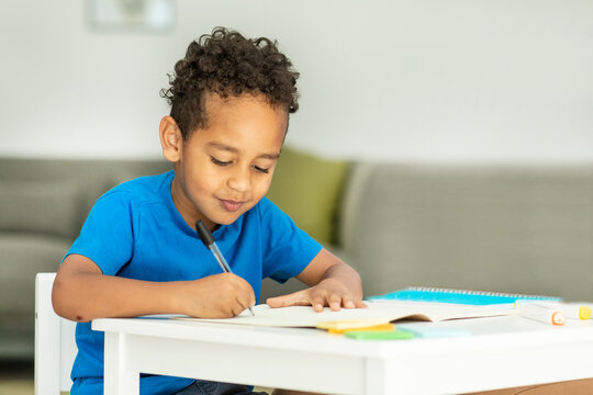 Portrait of an African-American boy sitting at a table and drawing in a notebook, Copying Space