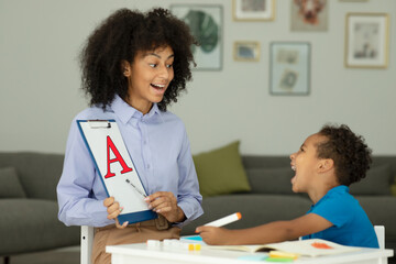 Cute little boy, learning the alphabet with his sister, teacher sitting together at the table