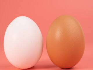 Chicken eggs on a pink background. White and brown egg on a pink background.