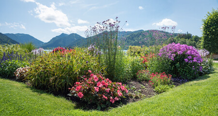 beautiful spa garden Schliersee with colorful flowerbed. view to bavarian alps