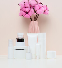 Fototapeta na wymiar White plastic jars and tubes for liquid cosmetics on a white background. Branding, advertising