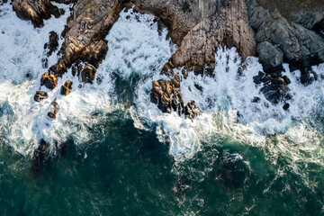 Aerial view of a rocky seashore in the resort town of Sozopol - Bulgaria. Waves crashing into rocks captured by drone.