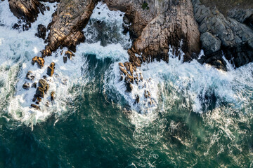 Aerial view of a rocky seashore in the resort town of Sozopol - Bulgaria. Waves crashing into rocks captured by drone.