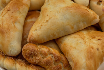 Freshly baked pies and buns with a golden crust, triangular shape and pigtail