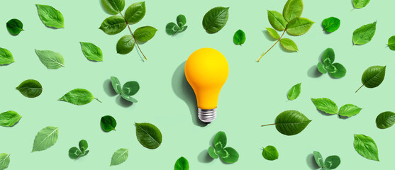 Yellow light bulb with green leaves - Flat lay