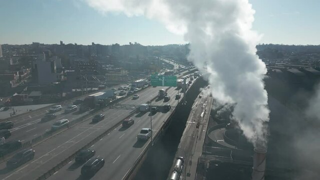 slomo flying counter clockwise around smoking smokestack and traffic in Brooklyn