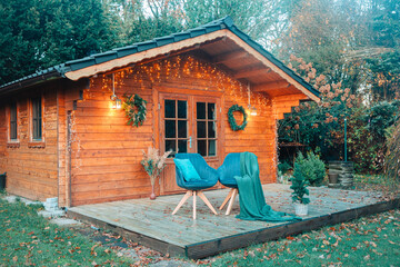 Beautiful wooden hut in the garden decorated with fairy lights. Christmas decorations in the...
