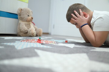 the boy is playing a board game. he looks at the cube and is surprised at the number he got. The...