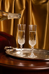 champagne is pouring from a bottle into a crystal glass in a luxurious interior