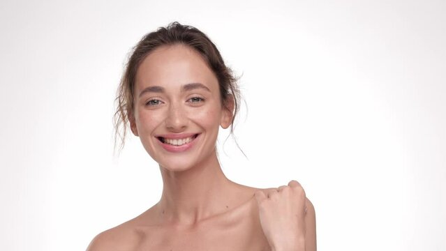 Beauty portrait of young woman touching her smooth skin in collarbone area. Skin care concept. Brunette hair Female model with fresh skin, white smile and natural facial makeup portrait. Close up.