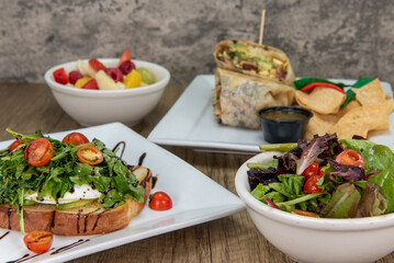 Amazing feast on the table with a mixed green salad and avocado toast featured up front to choose from