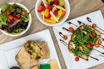Amazing feast on the table with avocado toast, breakfast burrito, fresh fruit, or mixed green salad to choose from