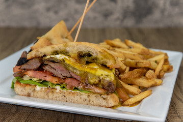 Layers of steak, eggs, cheese, and fresh vegetables, all contained in a baked ciabatta bun and served with fries