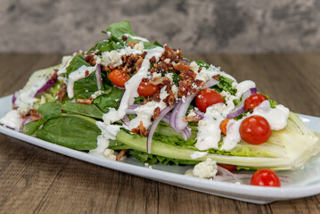 Very large romaine lettuce wedge salad piled high with fresh ingredients