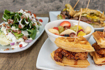 Amazing feast on the table with chicken and waffles, romaine salad, or breakfast sandwich to choose...
