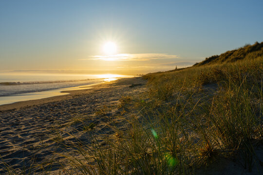 Beach view in silhouette looking into sun along Papamoa surf beach, Tauranga