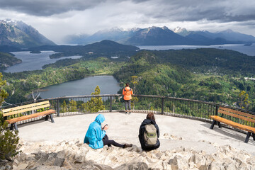 Tres jóvenes damas están observando las bellezas del Cerro Campanario en Bariloche Argentina. - obrazy, fototapety, plakaty