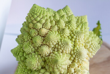 close-up cabbage Romanesco broccoli on a round wooden cutting board on a white background