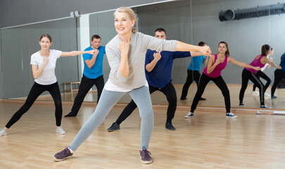Fototapeta na wymiar Portrait of dancing mature woman practicing vigorous swing during group training in dance studio