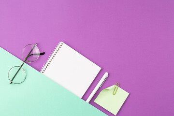 Spiral notepad with pen, note sheet and glasses.