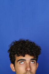 Fototapeta na wymiar Portrait of young African American male with curly hair looking at camera against blue background