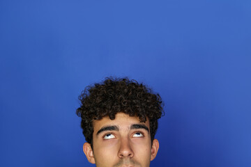 Obraz premium closeup portrait headshot cropped face above lips of cute men looking up isolated on blue studio wall background with copy space above head. Human face expressions, emotions