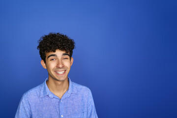 Fototapeta na wymiar Smiley teenager looks excited, isolated on a blue background.