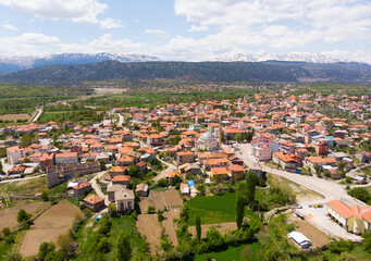 Fototapeta na wymiar Aerial view of typical Turkish small town Yesildag of Burdur province on sunny spring day with snowy mountain range in background..