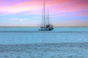 Fototapeta premium bateau voilier au Coucher de soleil rose et lagon bleu turquoise de Polynésie