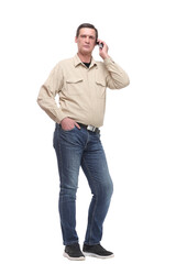 Serious young casual man standing with a hand in his pocket and speaking on the phone