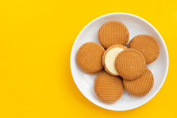 Custard cream sandwich biscuits on yellow background.