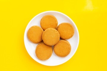 Custard cream sandwich biscuits on yellow background.