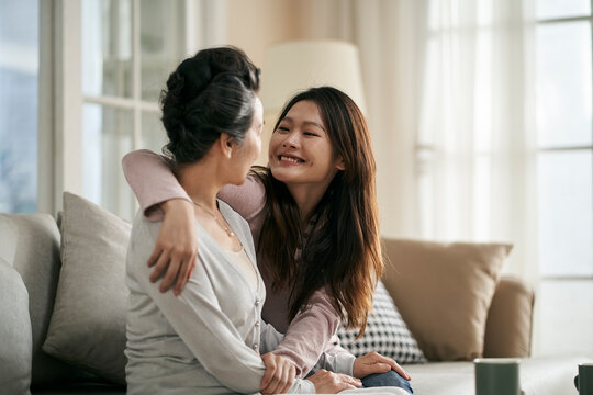 asian adult daughter and senior mother chatting at home