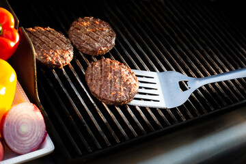 grilling burgers on a grill with a spatula