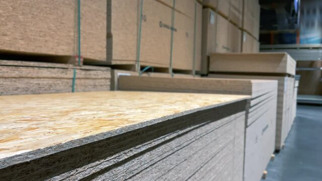 Stacks of sheet chipboard lie in the warehouse of a woodworking factory
