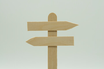 Poste indicador de cruce de caminos de madera con flechas opuestas, sobre fondo blanco