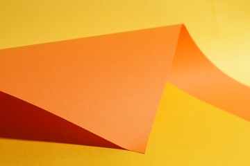 Orange paper sheet on yellow background, closeup