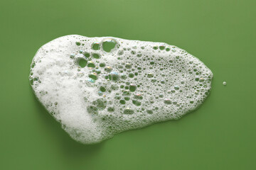 Smudge of white washing foam on olive background, top view