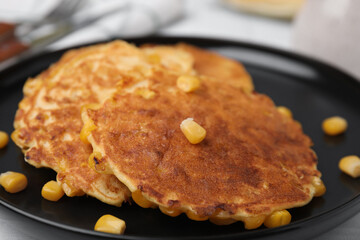 Tasty corn pancakes on black plate, closeup