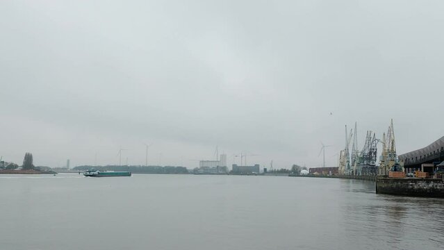 Antwerp harbour in Belgium at foggy grey morning. Ship passing by on waterway