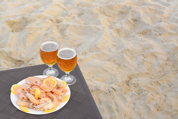 Fototapeta na wymiar Cold beer in glasses and shrimps served with lemon on beach