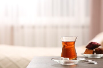 Glass with traditional Turkish tea and cookies on table indoors. Space for text