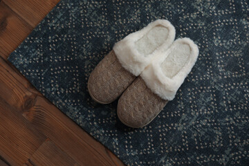 Fototapeta na wymiar Stylish door mat and slippers on wooden floor, top view