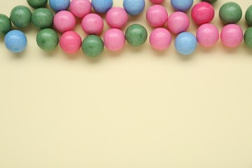 Many bright chewy gumballs on beige background, flat lay. Space for text