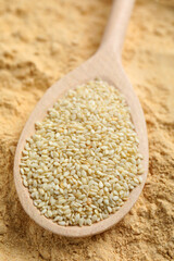 Sesame flour and spoon with seeds, closeup