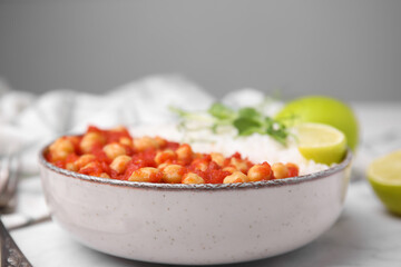 Fototapeta na wymiar Delicious chickpea curry with rice in bowl on white marble table, closeup